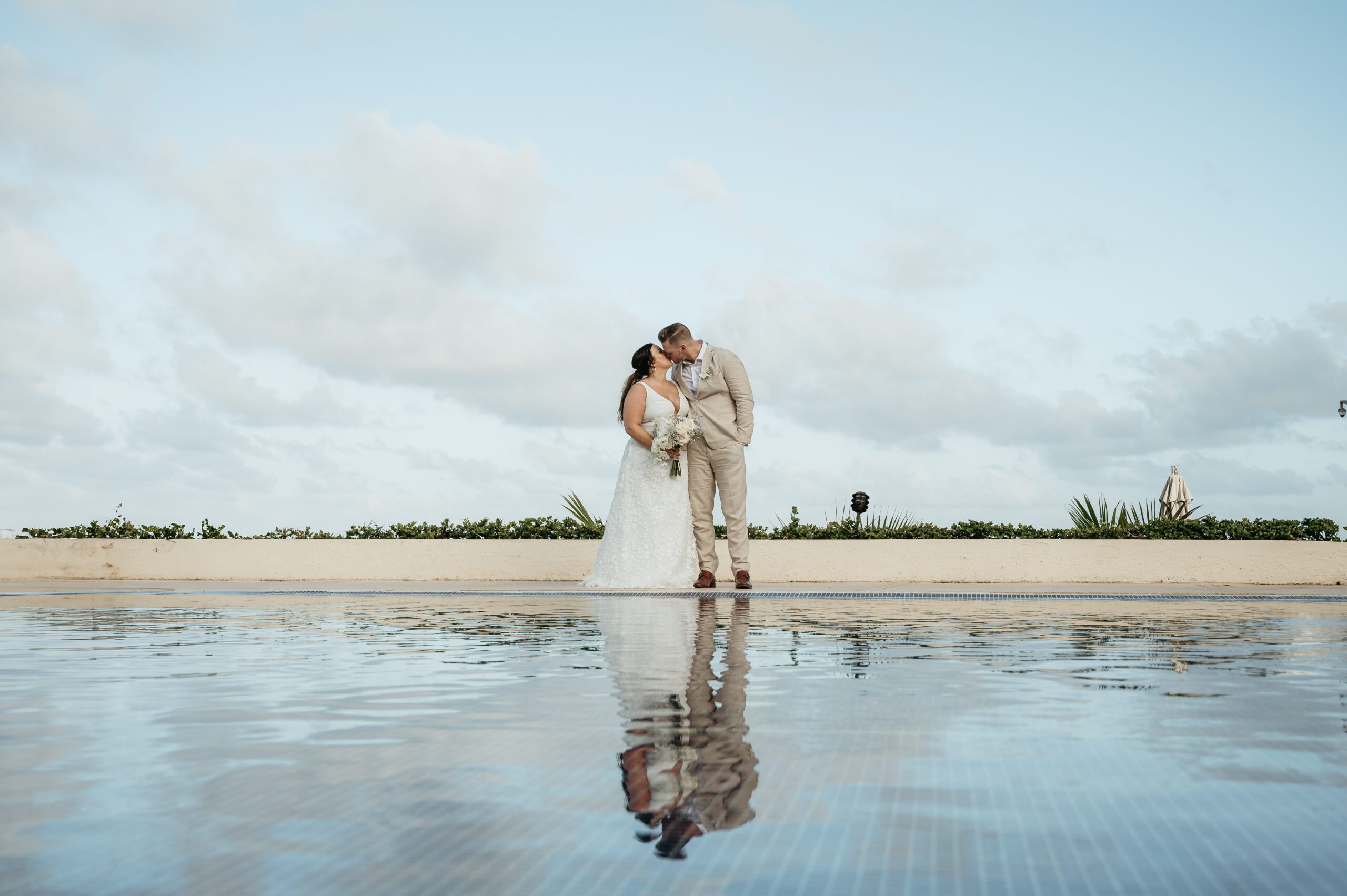 Bride and groom kissing on the beach during a destination wedding at a luxury all-inclusive resort in Mexico.
